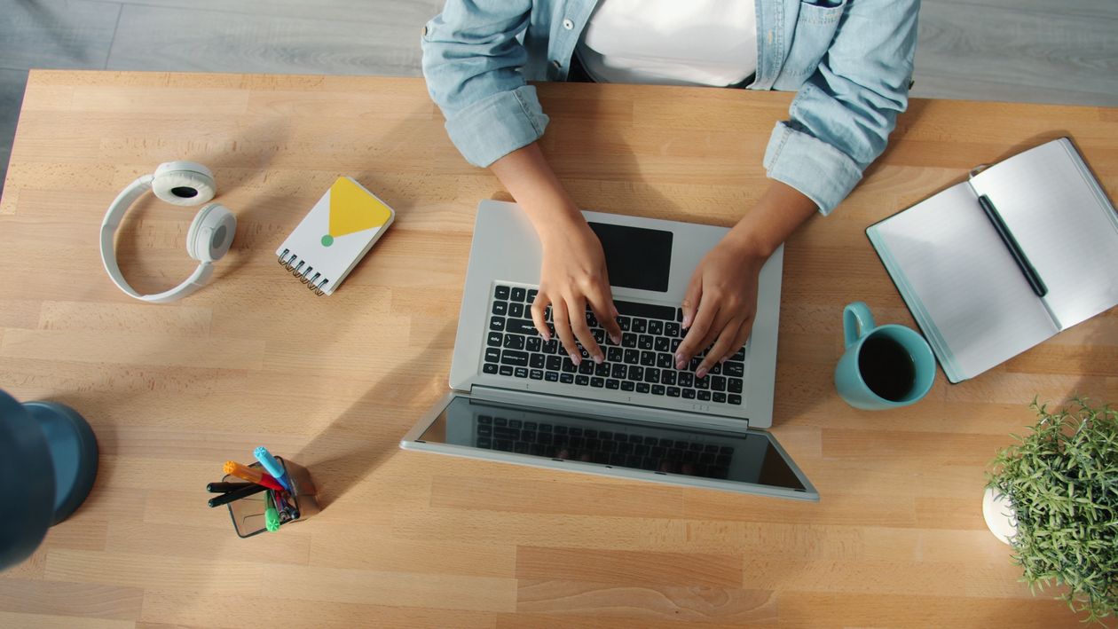 Overhead view of a workspace with a laptop, notebook and headphones