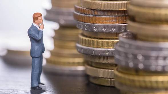 Businessperson analysing stacks of coins — comparing subscription costs