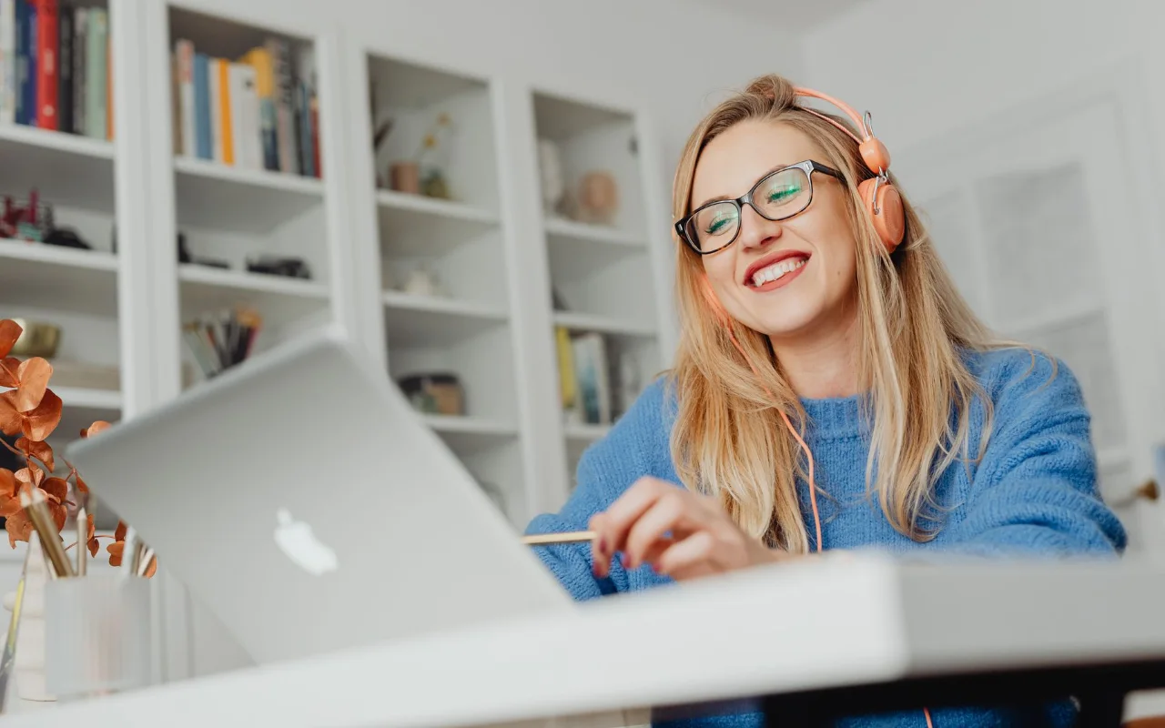 Student with headphones studying beside a laptop